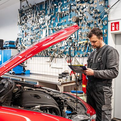 Autohaus Sayler in Ulm Mitarbeiter vor offener Motorhaube füllt Checkliste aus